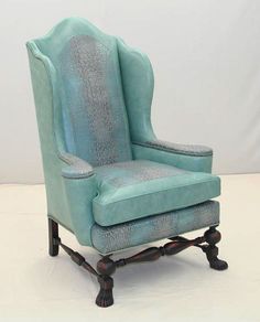 a blue wingback chair sitting on top of a white floor next to a wall