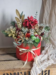 a red box with flowers and greenery in it