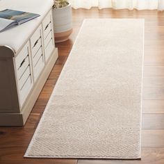 a white rug is on the floor in front of a window with curtains and drawers