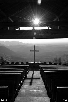 the sun shines brightly over rows of pews in a church with mountains in the background