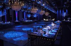 a banquet hall with blue lighting and chandeliers