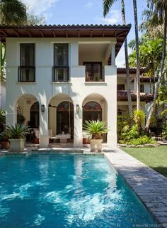 a house with a swimming pool in front of it and palm trees around the pool