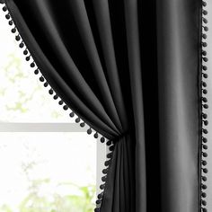 a black curtain with pom - poms hanging from it's side in front of a window