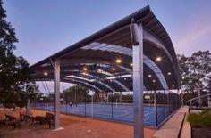 an outdoor tennis court is lit up at night with lights shining on the courts and benches