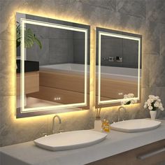 two sinks and mirrors in a bathroom with lights on the wall above them are white flowers