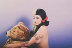 a woman with tattoos holding a teddy bear