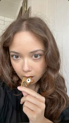 a young woman is eating a cookie with an eyeball in it's mouth