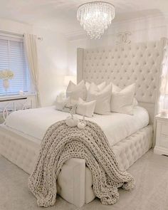 a white bed with lots of pillows and blankets