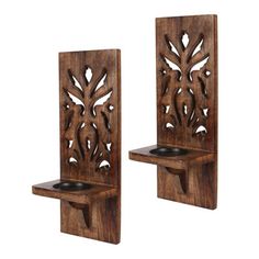 two wooden wall mounted candle holders with carved designs on them, one holding a tea light holder