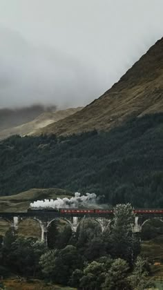 a train traveling over a bridge in the mountains