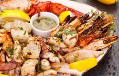 a plate full of shrimp, scallops and asparagus with lemon wedges