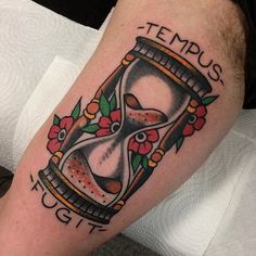 a tattoo with an hourglass and flowers on it