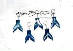 three blue dolphin keychains hanging from chains on a white background with the words dragon beach resort written above them