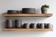 two wooden shelves with plates and cups on them, one holding a potted plant