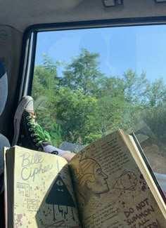 a person sitting in the back seat of a car with an open book on their lap