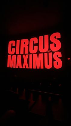 the words circus maximus are lit up in red and black colors on a dark background