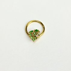 a gold ring with two green leaves on the front and one small leaf on the back