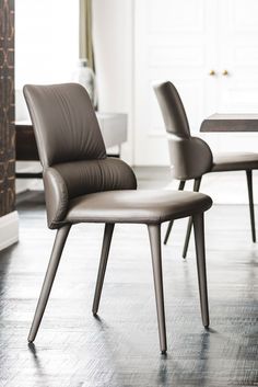 two brown chairs sitting next to each other on top of a hard wood floored floor