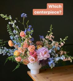 a vase filled with lots of flowers on top of a wooden table next to a sign that says which centerpiece?