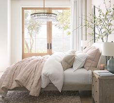 a bedroom with a bed, nightstands and a chandelier hanging from the ceiling