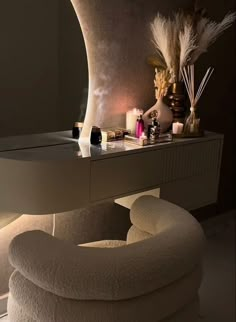 a white chair sitting in front of a mirror next to a table with candles and other items on it