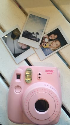 a pink camera sitting on top of a counter next to pictures and a wall hanging