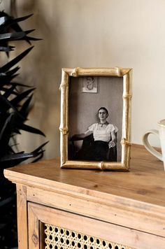 an old photo sitting on top of a wooden table next to a cup and saucer