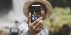 a man taking a selfie with his cell phone in front of him while wearing a hat