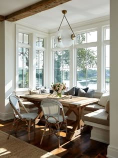 a dining room table surrounded by chairs in front of large windows with lots of natural light