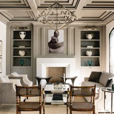 a living room filled with furniture and a chandelier hanging from the ceiling over a fire place