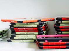 several different colored laptops are stacked on top of each other, one is red and the other is green