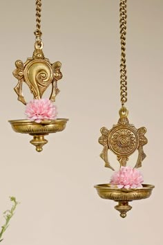 two gold vases with pink flowers hanging from them