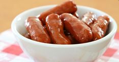 a white bowl filled with hot dogs sitting on top of a checkered table cloth