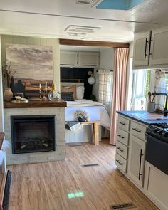 a kitchen and living room are shown with wood floors, white cabinets, and a fireplace