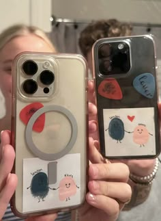 two people holding up their cell phones with stickers on them and one has a phone case