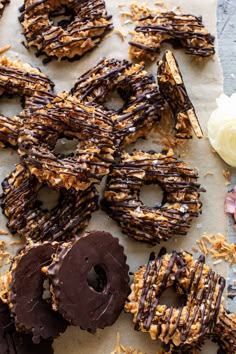 chocolate covered doughnuts with sprinkles sitting on top of paper next to flowers