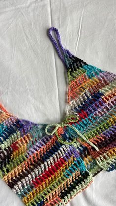 a multicolored crocheted bag laying on top of a white bed sheet