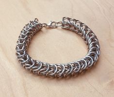 a silver chain bracelet sitting on top of a wooden table