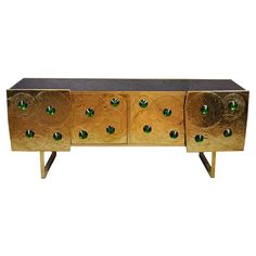 a gold and black cabinet with green glass knobs on the doors, sideboard