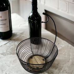 two bottles of wine sitting on top of a counter next to a wire basket and bottle opener