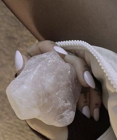 a woman's hand with white manies holding a large rock in her purse