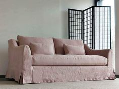 a pink couch sitting on top of a white floor next to a tall black window