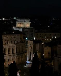 the city is lit up at night with lights on and buildings in the foreground