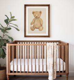 a baby's crib with a teddy bear hanging on the wall next to it