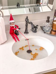 an elf is washing his hands in the bathroom sink with soapy water on the counter