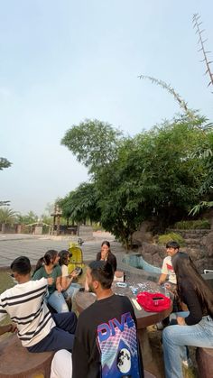 group of people sitting on stone bench near trees