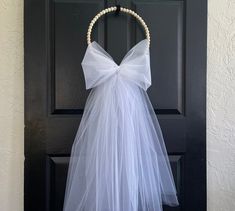 a wedding dress hanging on a door with a white ribbon around the waist and bow