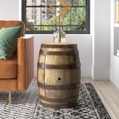 a living room with a couch, chair and wooden barrel table in front of a window