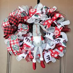 a christmas wreath hanging on the front door decorated with stockings and santa's helpers