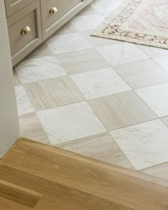 a kitchen with white cabinets and wood flooring on the walls, along with an area rug that looks like it has been tiled